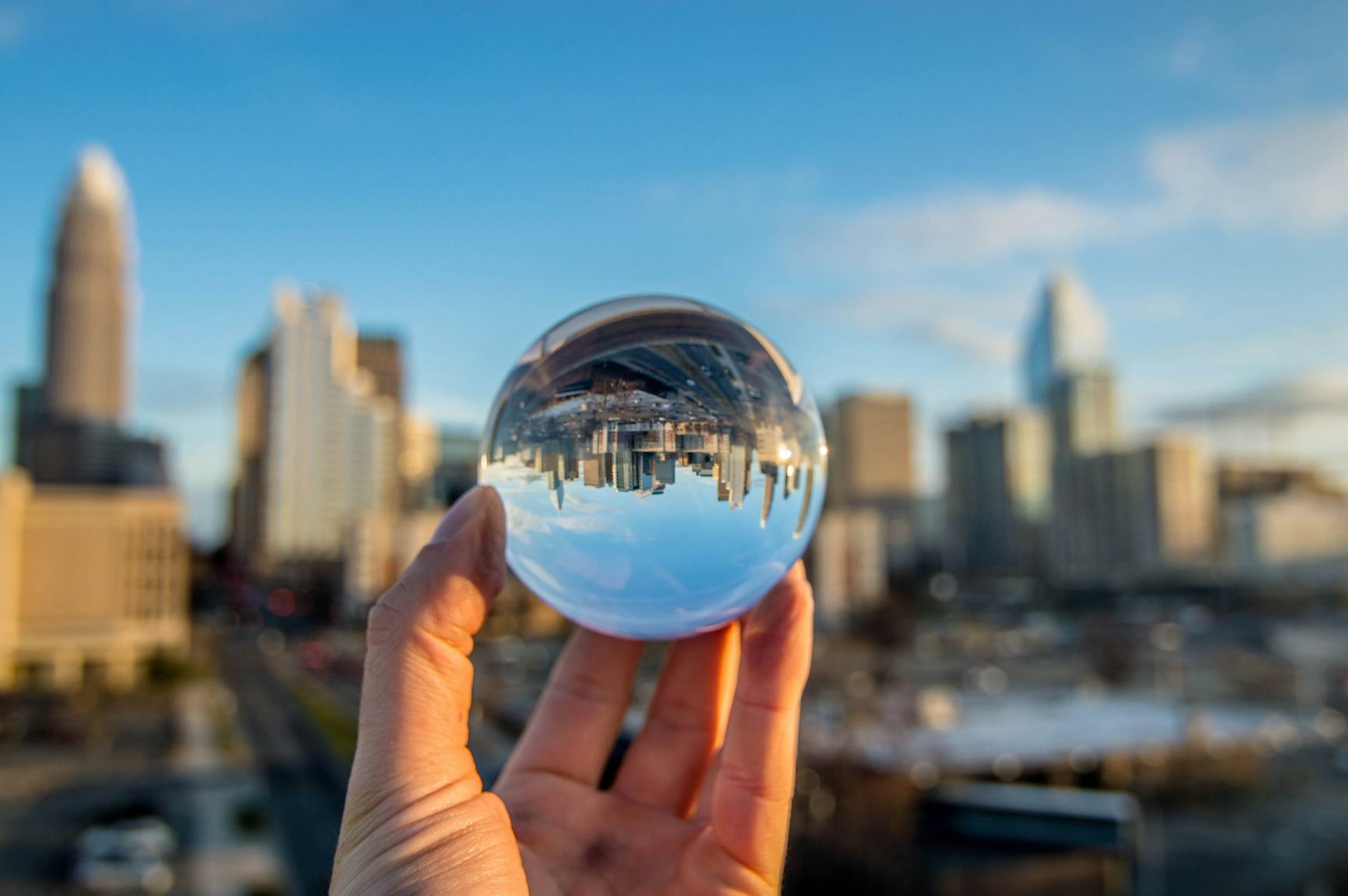 Hand holding a glass ball up to a city skyline